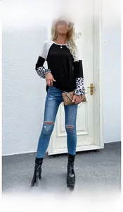 Outdoor model show of a black waffle knit top with leopard print cuffs and white shoulders
