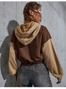 Back view of a cropped color-block hoodie with brown body and khaki sleeves on a model