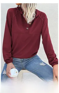 Detail of wine red hooded sweatshirt featuring raglan sleeves and amber button neckline