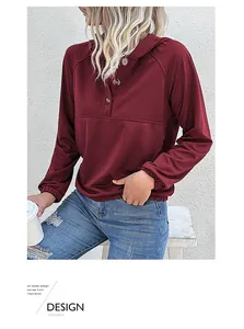 Detail view of burgundy hoodie featuring three decorative buttons and raglan sleeves