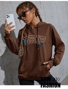 Detail of oversized brown hoodie featuring white DRIP text and blue butterfly print