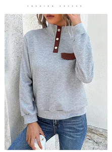 Detail of grey quilted sweatshirt showing metal buttons and brown leather patch accents