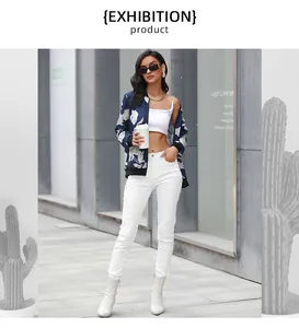 Street style shot of navy floral bomber jacket paired with white pants and ankle boots