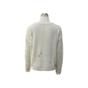 Détail d'un pull en maille blanche vieillie avec coupe épaule nue et trous ajourés