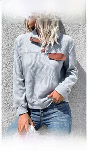 Detail of grey quilted sweatshirt showing textured fabric and brown buttoned collar