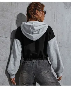 Detail of cropped hooded sweatshirt featuring contrast sleeves and elasticated hemline