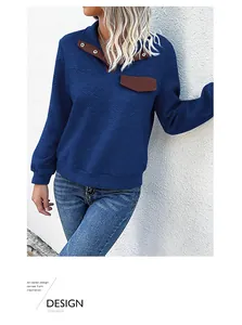 Detail of blue textured sweatshirt featuring buttoned stand collar and brown contrast pocket