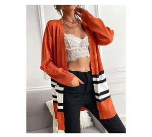 Detail of orange knit cardigan featuring black and white striped hem and loose fit design