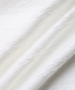 Gros plan sur un tissu blanc texturé avec motif ondulé en 3D et texture tricotée douce