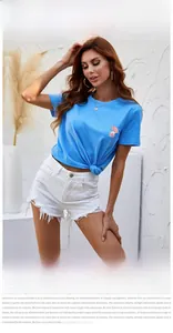 Detail of blue cotton T-shirt with perfume floral print and frayed white denim shorts