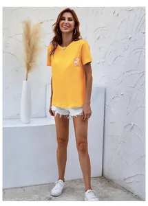 Detail of a ginger yellow cotton T-shirt featuring floral and perfume bottle prints