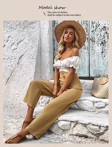 Detail of high-waist khaki trousers with decorative waist buttons and loose straight leg fit