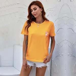 Women's orange crew neck t-shirt with floral print paired with denim shorts