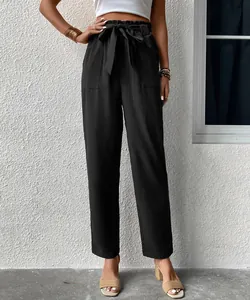 Detail of high waisted black trousers featuring paperbag waist with adjustable tie belt