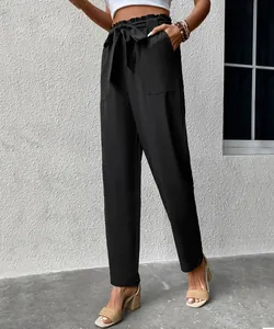 Detail of high-waist paperbag trousers with tie-belt and textured cotton fabric