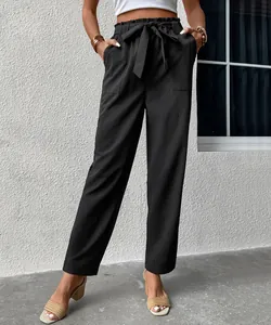 Detail of black paper-bag high waist trousers with textured fabric and matching tie belt