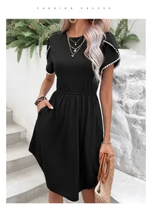 Détail d'une robe noire trapèze avec manches en dentelle blanche et poche latérale pratique
