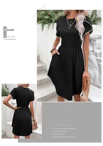 Détail de la robe trapèze noire avec manches pétales à pompons blancs et poches pratiques