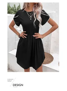 Détail de la robe trapèze noire avec bordure ondulée blanche aux manches et taille