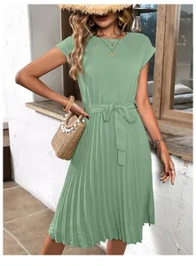 Detail of light green pleated dress showing flutter sleeves and tie-waist in a resort style