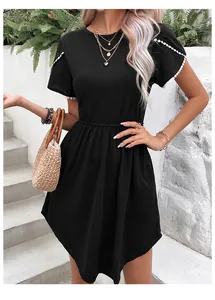 Détail de la robe T-shirt noire avec poignets en dentelle blanche et poches latérales