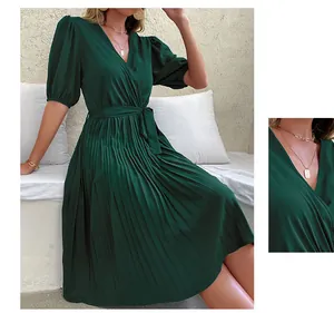 Detail of dark green V-neck pleated dress with tie waist and puff sleeves close-up view