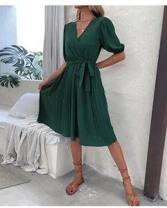 Detail of V-neck pleated green dress with waist tie and elegant short puff sleeves