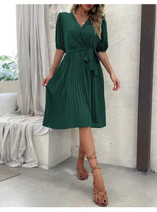 Detail of V-neck dark green pleated dress with puff sleeves and waist tie belt