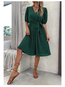 Detail of V-neck dark green pleated dress with puff sleeves and tie waist