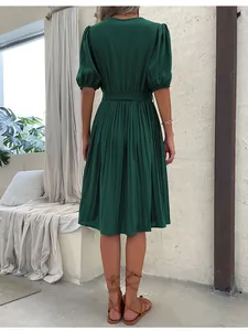 Detail view of the back of a dark green short-sleeved pleated summer dress with a tie waist