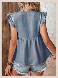 Detail der blauen ärmellosen Bluse mit Schweizer Punkten und Rüschen am Ärmel
