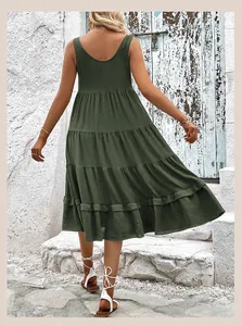 Back view of a sleeveless dark green tiered midi dress in a rustic outdoor setting