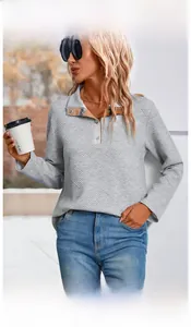 Detail of grey waffle knit sweatshirt featuring half-button collar and plaid inner lining