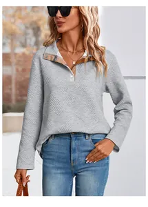 Detail of light grey quilted texture sweatshirt with brown plaid lining on button collar