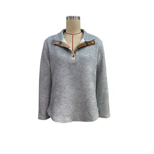 Close-up of quilted gray sweatshirt with brown plaid lining and buttoned collar detail