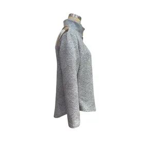 Detail of grey quilted texture fabric and khaki shoulder patchwork on a long sleeve pullover