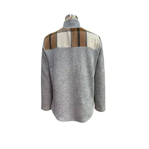 Detail of grey textured fabric with classic brown plaid patchwork on high-neck top