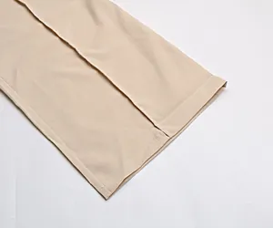 Gros plan détaillé de la texture du tissu crêpe beige et des coutures de l'ourlet du pantalon