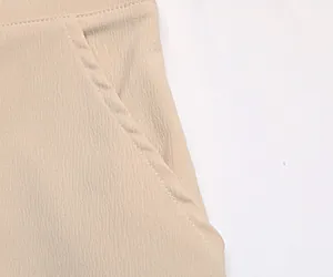 Détail de la poche latérale et des coutures sur un pantalon large beige en sergé