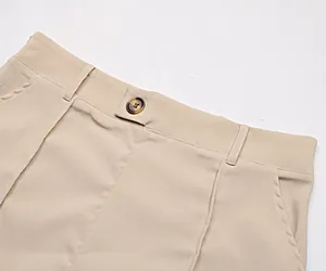 Détail du pantalon large kaki avec bouton en écaille et passants de ceinture cousus