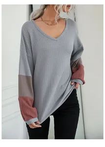 Detail of grey V-neck waffle knit sweater with contrast patchwork long sleeves