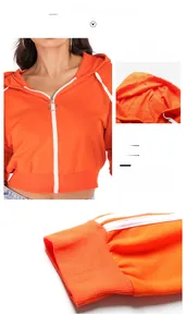 Detail view of bright orange cropped hoodie featuring a zip closure and white drawstring hood