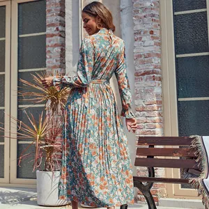 Robe longue plissée à fleurs avec ceinture, présentée dans un décor extérieur naturel