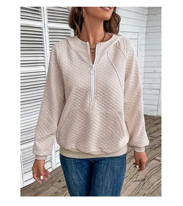 Detail of beige quilted hoodie featuring half-zip neckline and textured waffle pattern