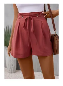 Close-up of brick red high waisted pleated shorts with matching tie belt and metal eyelets