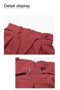 Detail of high-waisted paperbag shorts with brick red fabric, eyelets, and drawstrings