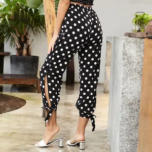 Polka dot high waist cropped trousers with side slit and bow tie in a stylish outdoor setting