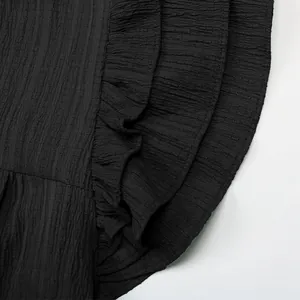 Vue détaillée des volants noirs et de la texture plissée verticale du tissu sur la robe d'été