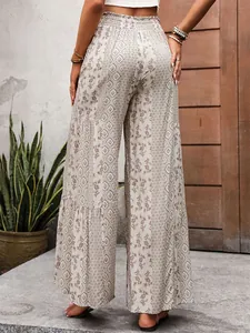 Detail view of high waisted smocked waist and bohemian print on wide leg trousers