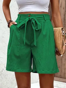 Close-up of emerald green high-waisted shorts with a bow tie and button front detail